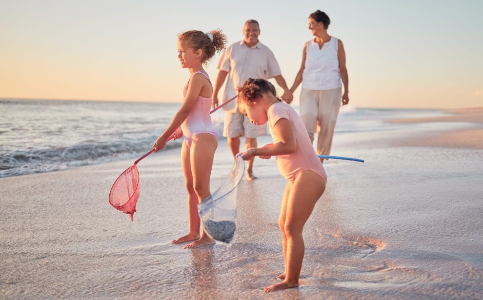 Grandparents and children at the beach with fishing nets and having fun. Young kids and senior couple enjoying holiday with grandkids and retirement together. Playing by the sea in summer with family Grandparents and children at the beach with fishing nets and having fun. Young kids and senior couple enjoying holiday with grandkids and retirement together. Playing by the sea in summer with family.