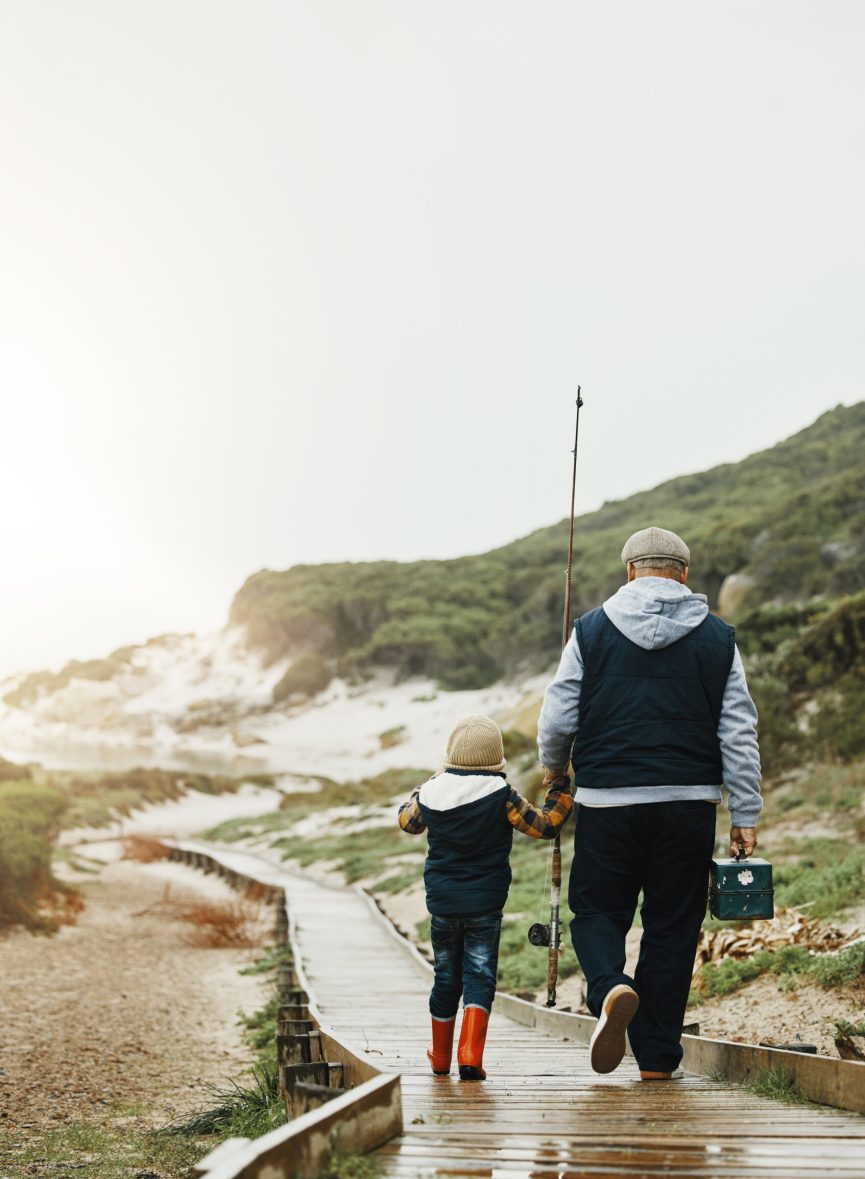 Walking, fishing and grandfather with child outdoor for lesson, leisure activity or hobby. Travel, bonding and back of senior man with kid to teach him to catch fish while on vacation or weekend trip Walking, fishing and grandfather with child outdoor for lesson, leisure activity or hobby. Travel, bonding and back of senior man with kid to teach him to catch fish while on vacation or weekend trip.